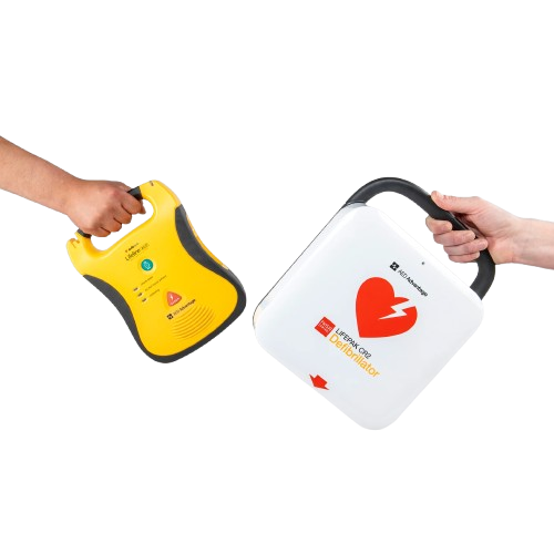 Two hands holding AED defibrillators — a Defibtech and a LIFEPAK CR2 — representing the AED trade-in program